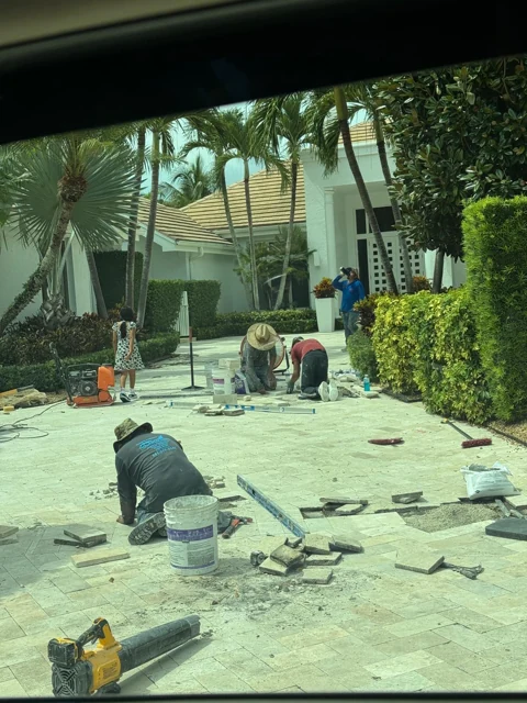 Paver installation in progress along an outdoor entryway with palm trees